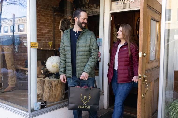 Man and woman walking out of Revolvr store in Bozeman, MT, with shopping bag.