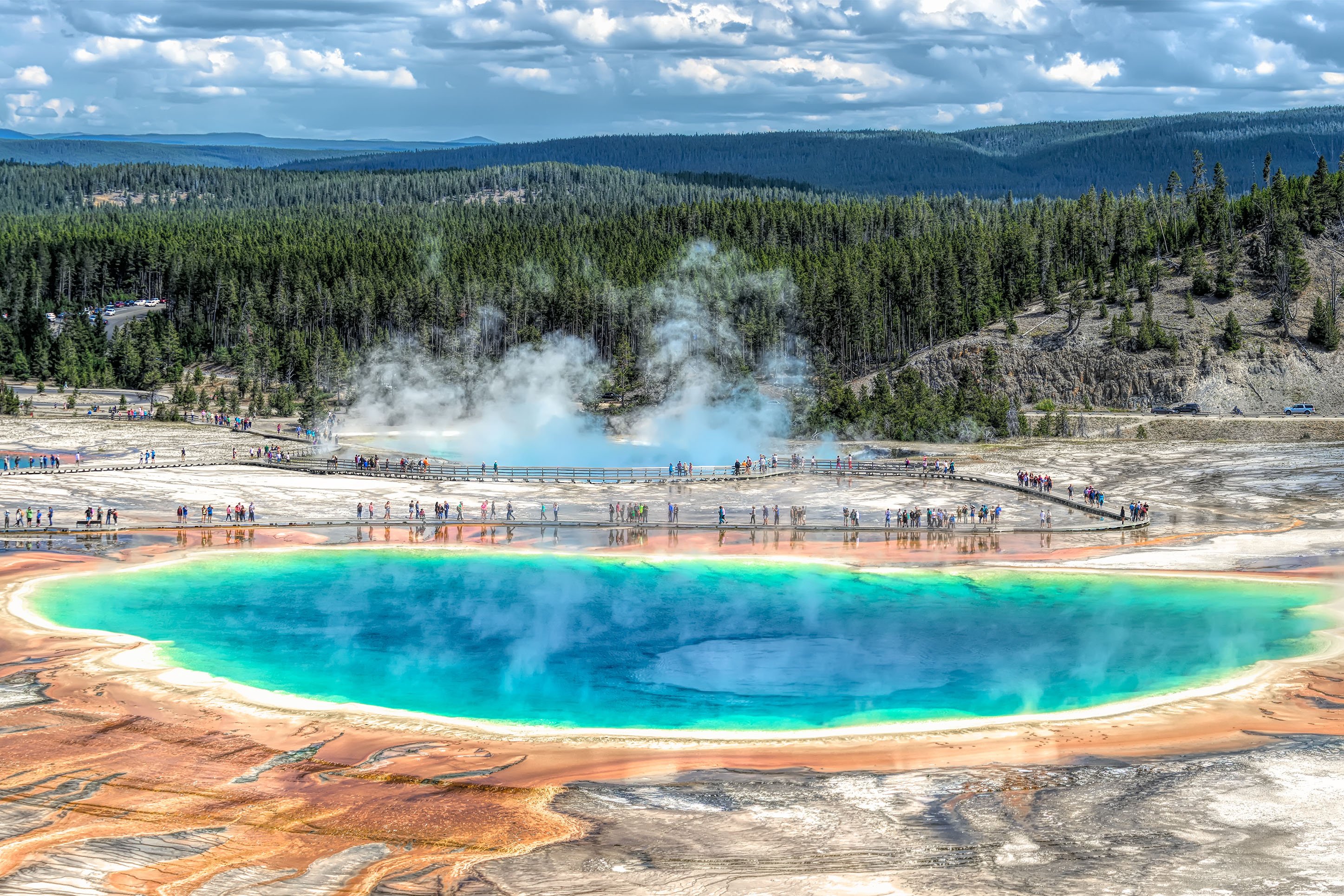 Photo of Grand Prismatic Spring with tourists exploring the surrounding boardwalks in Yellowstone