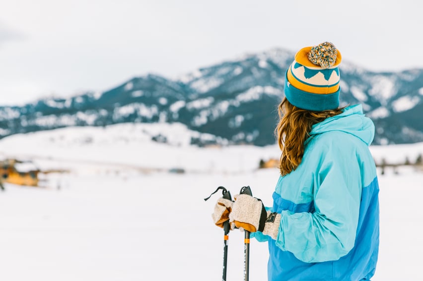 Woman cross country skiing in front of the mountains.