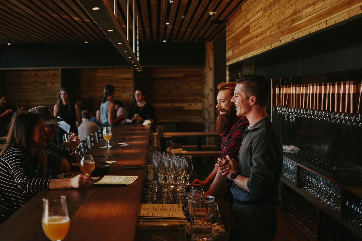 Bar staff and customers chatting inside Mountains Walking Brewery