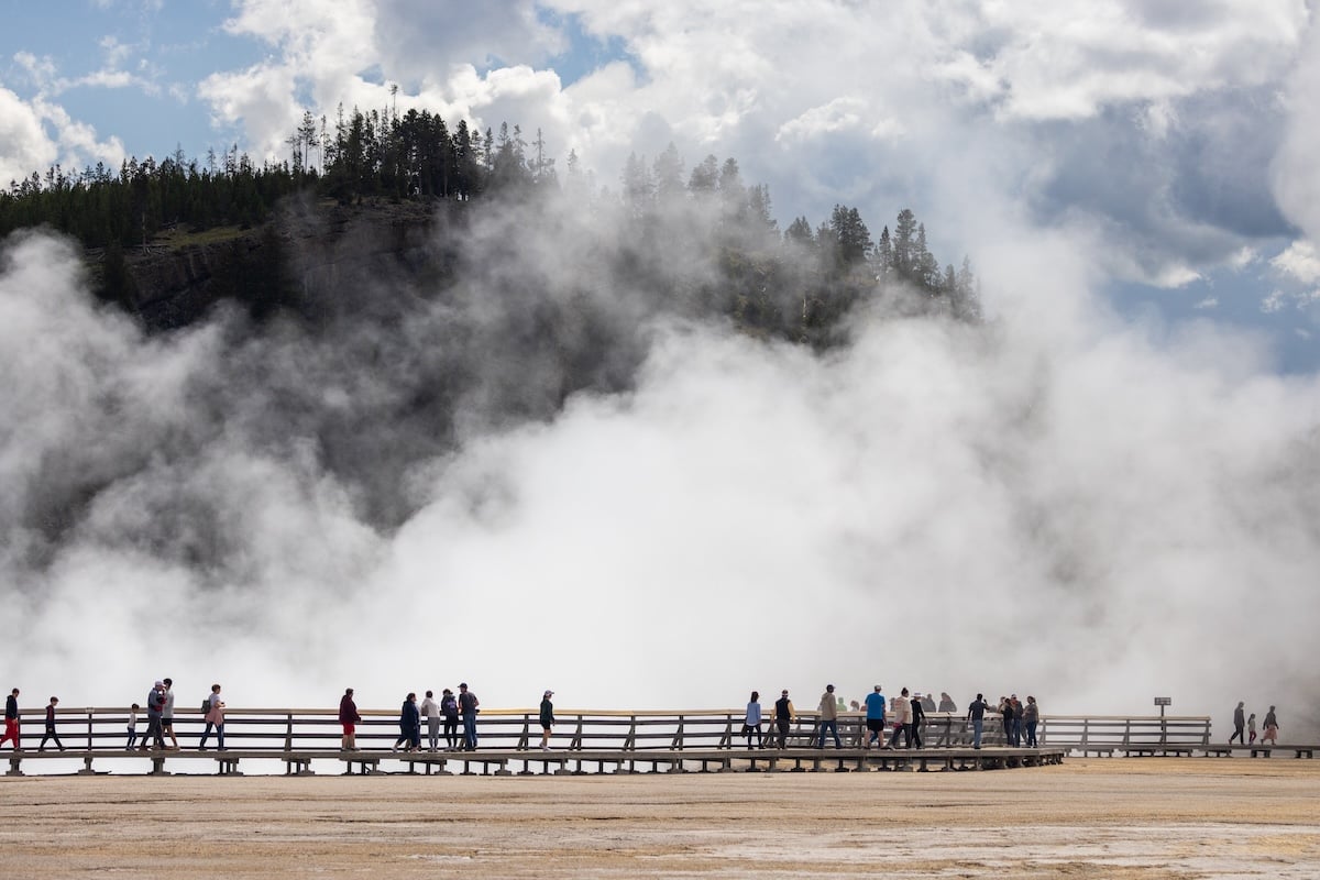 People walking on a boardwalk near a thermal feature in Yellowstone National Park