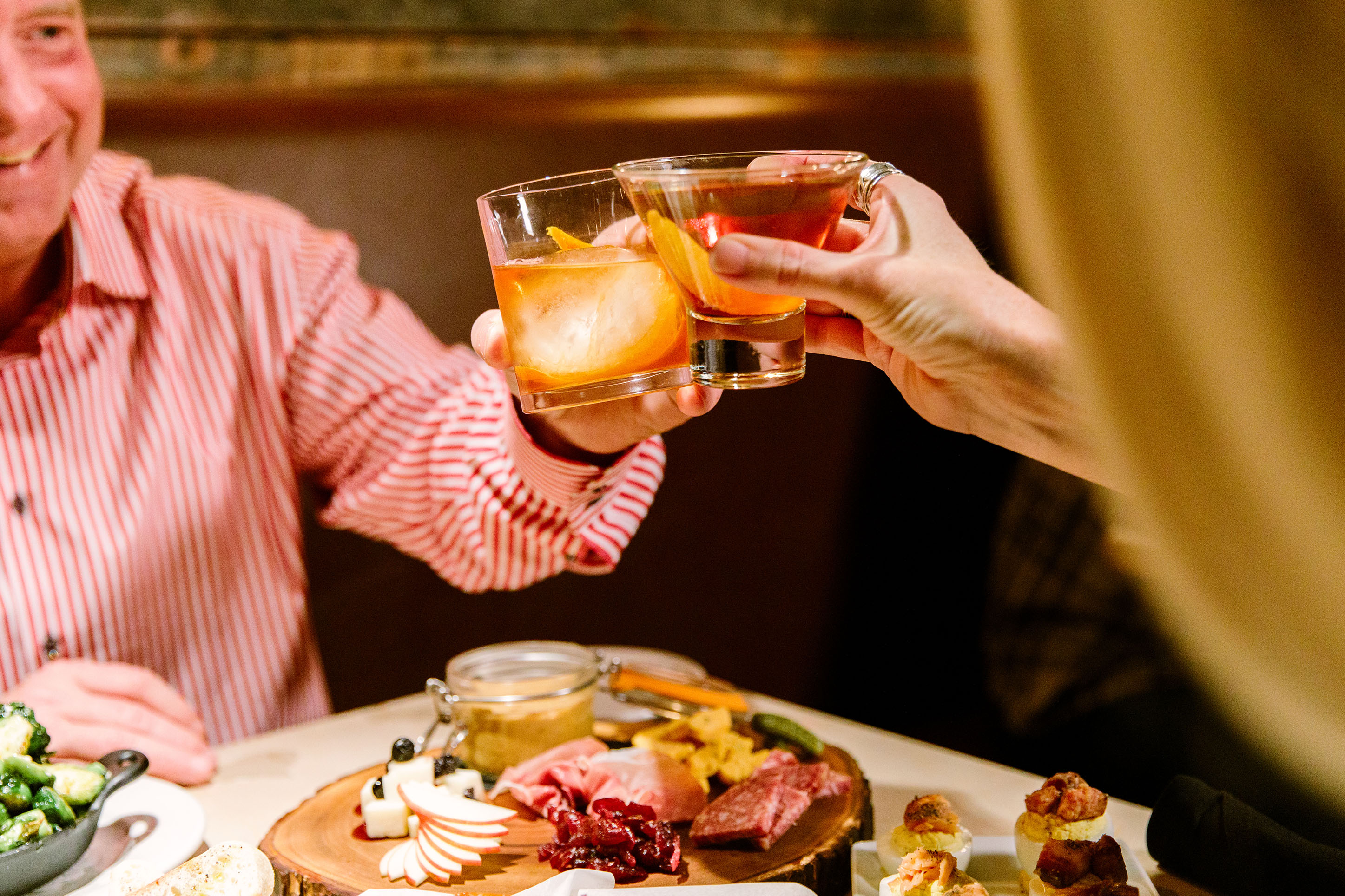 Photo of a couple clinking glasses with drinks