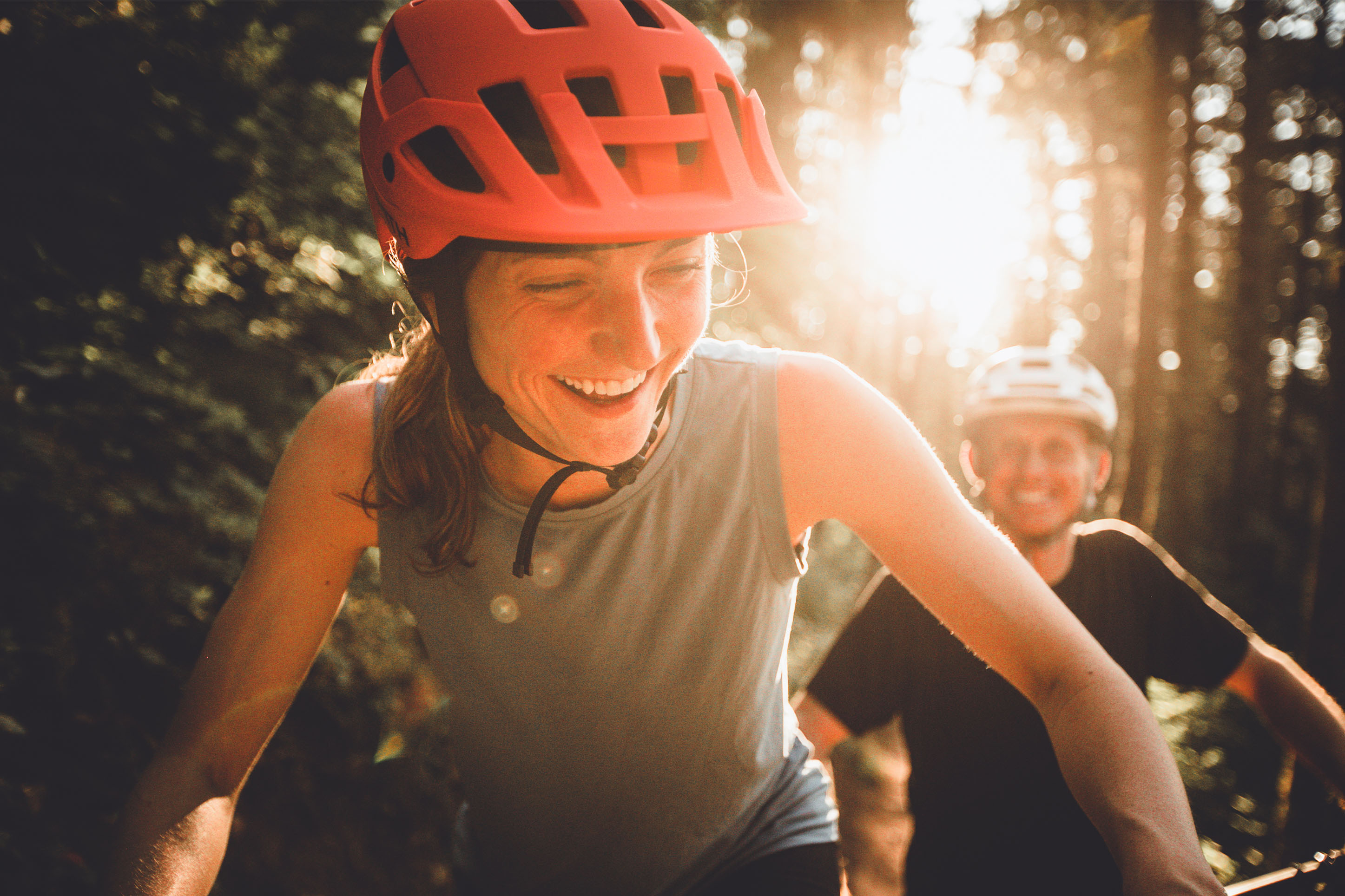 Photo of a woman riding a bike, smiling with man smiling on a bike behind her