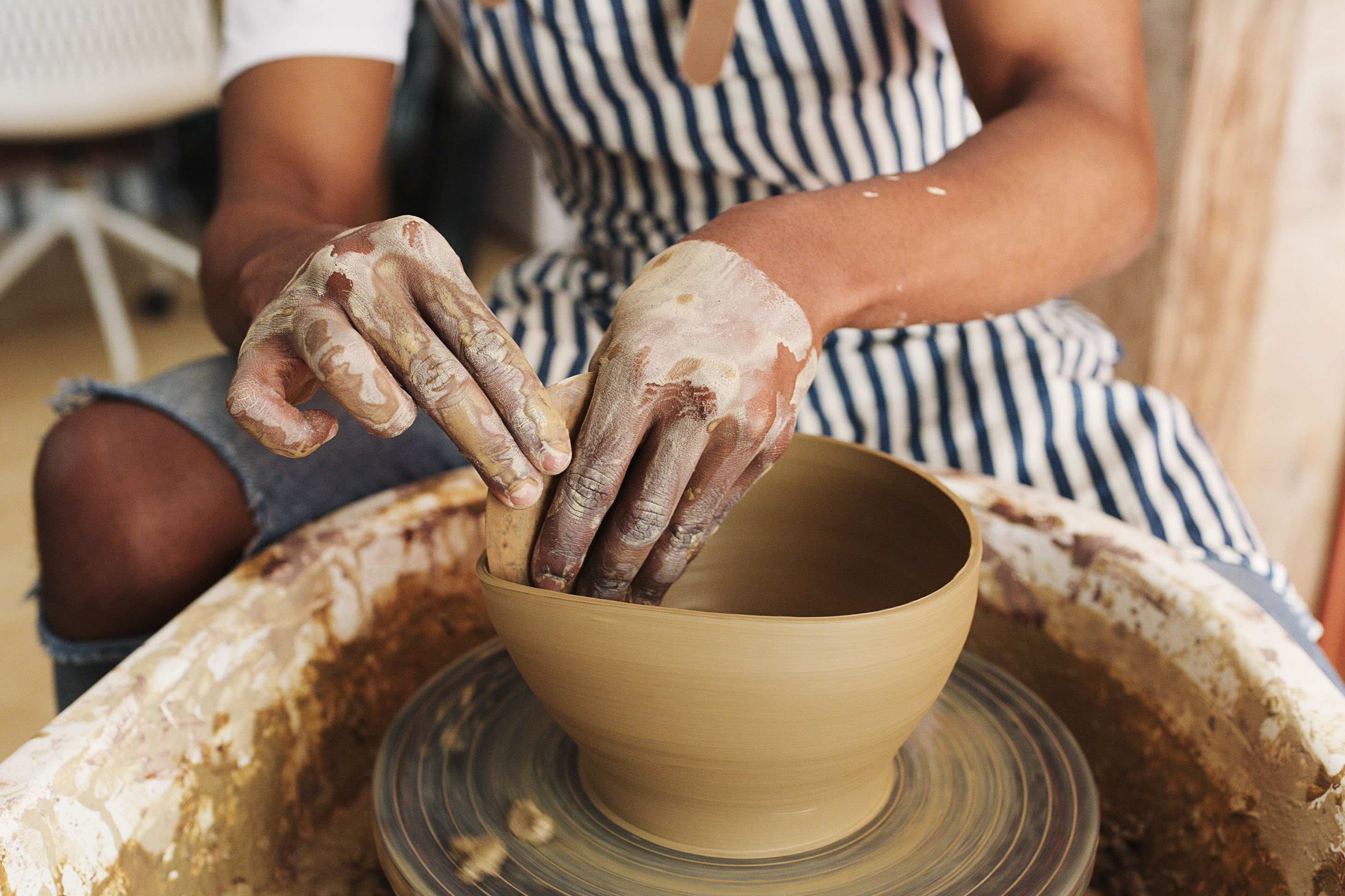 photo of a person of color working clay into a bowl