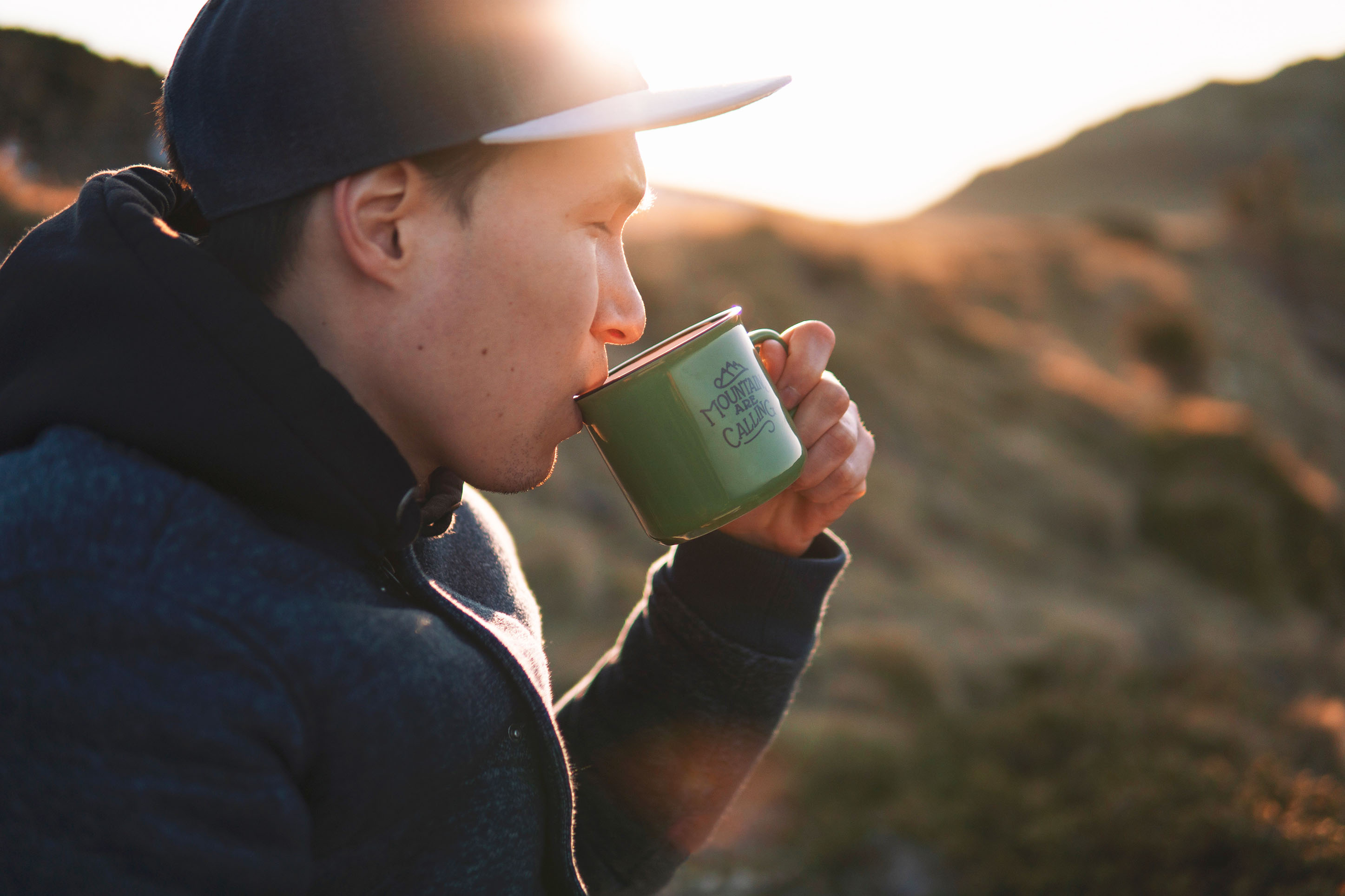 Photo of a man sipping coffee in the mountains