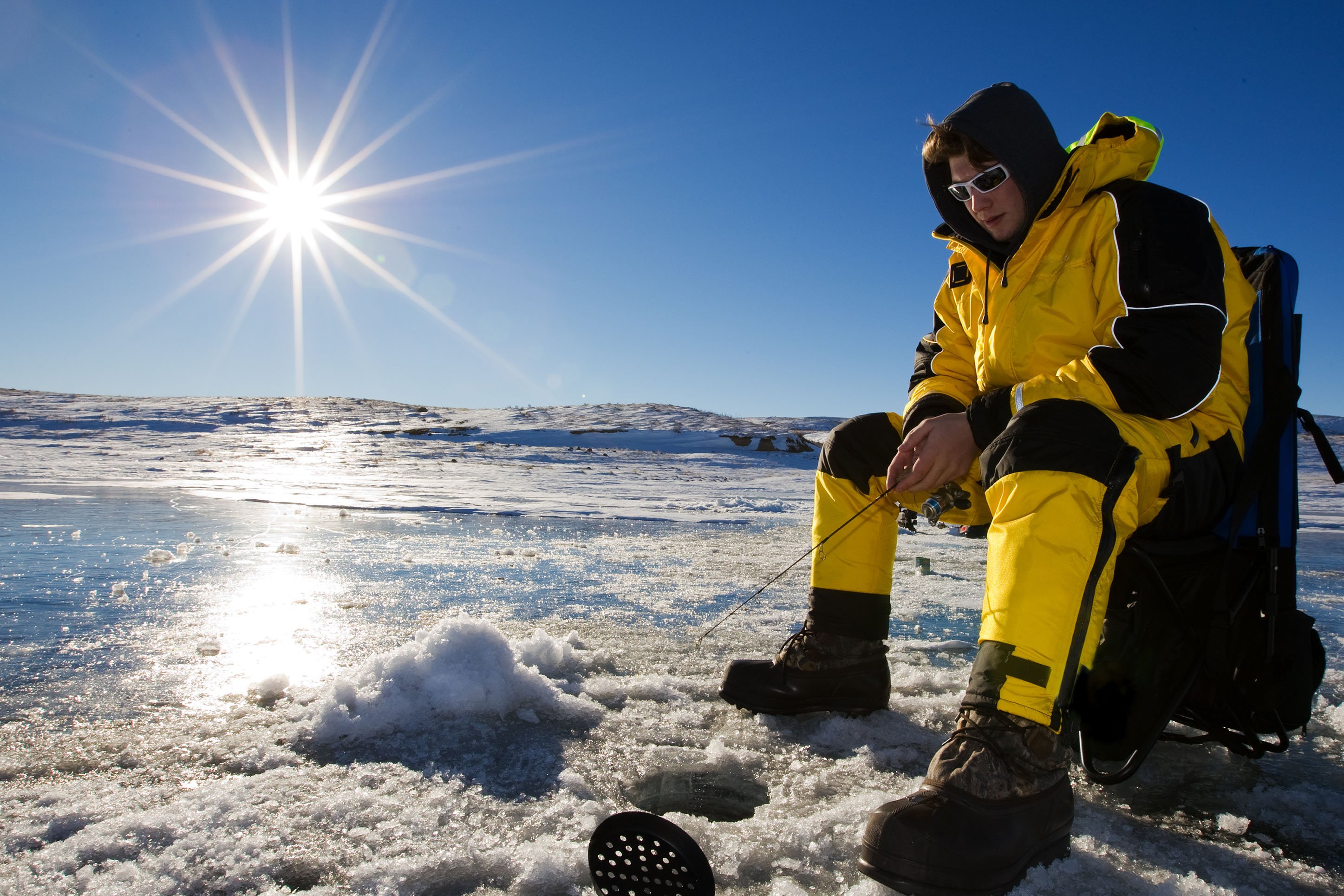 Ice fisherman sitting on a frozen lake with rod & reel