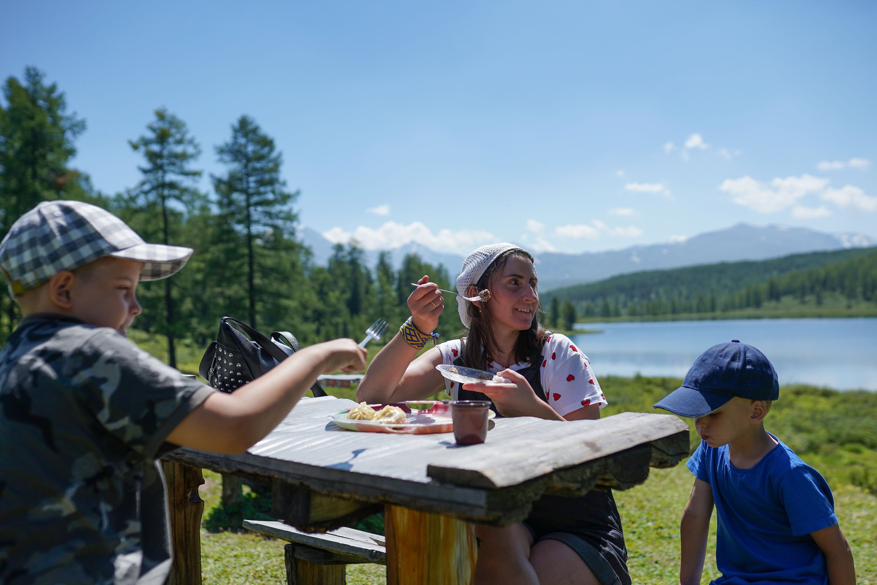 Family enjoying lunch at a picnic table alongside the water 