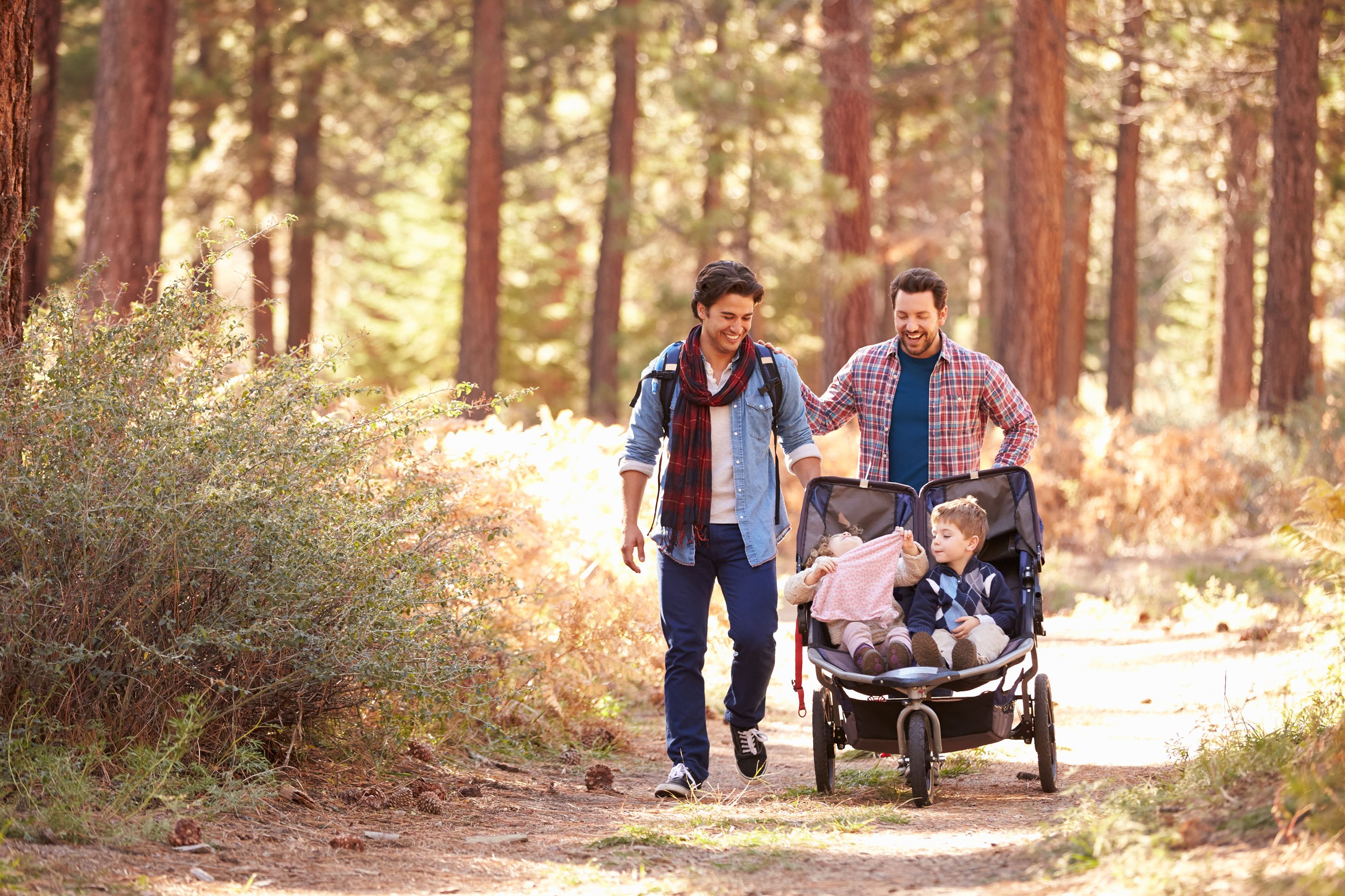 Two men pushing a baby stroller on a trail