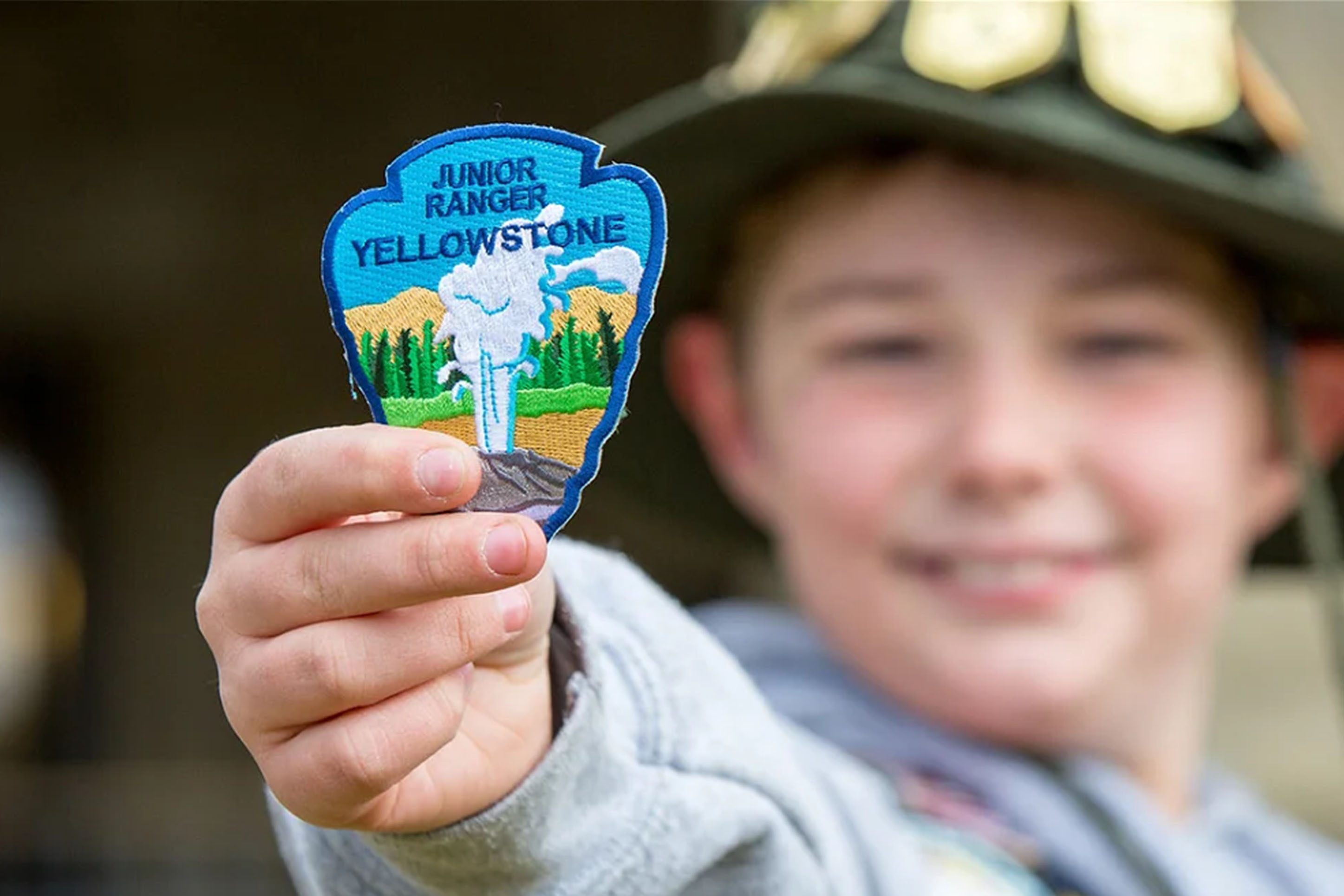 Boy showing is Junior Ranger badge from Yellowstone National Park. 