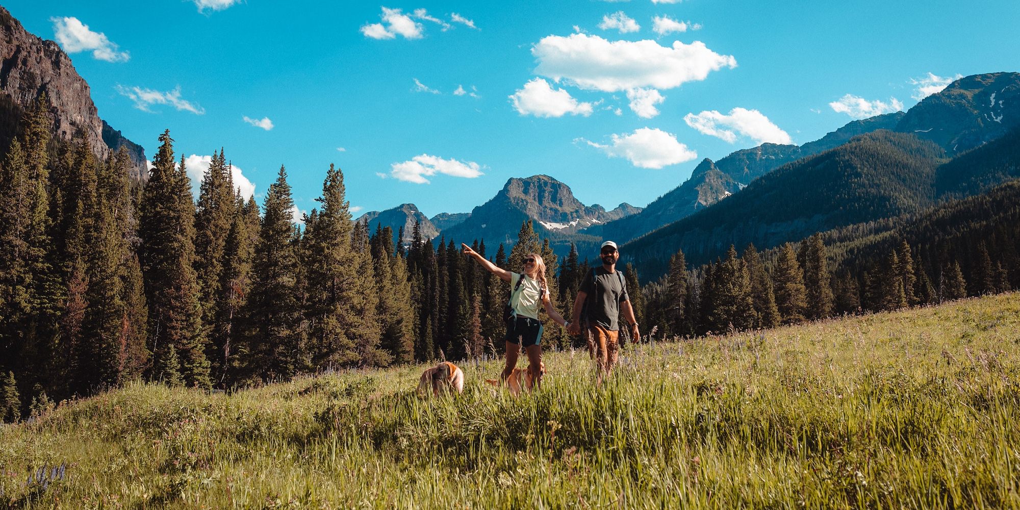 Two people hiking in Hyalite Canyon with mountains in the background.