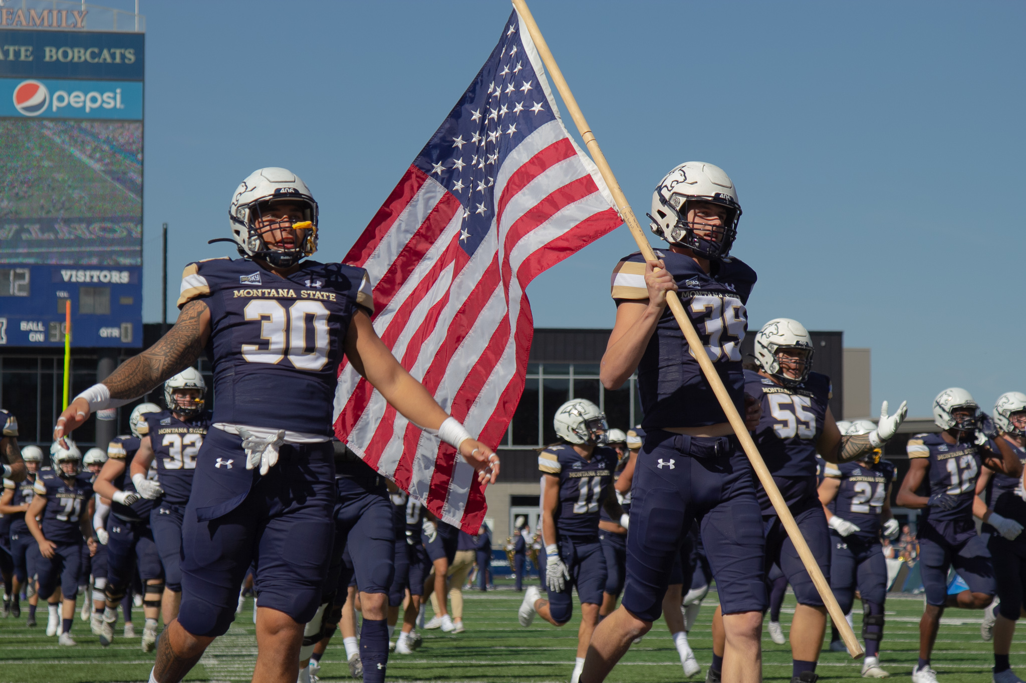 MSU football players running out onto the field with an American flag