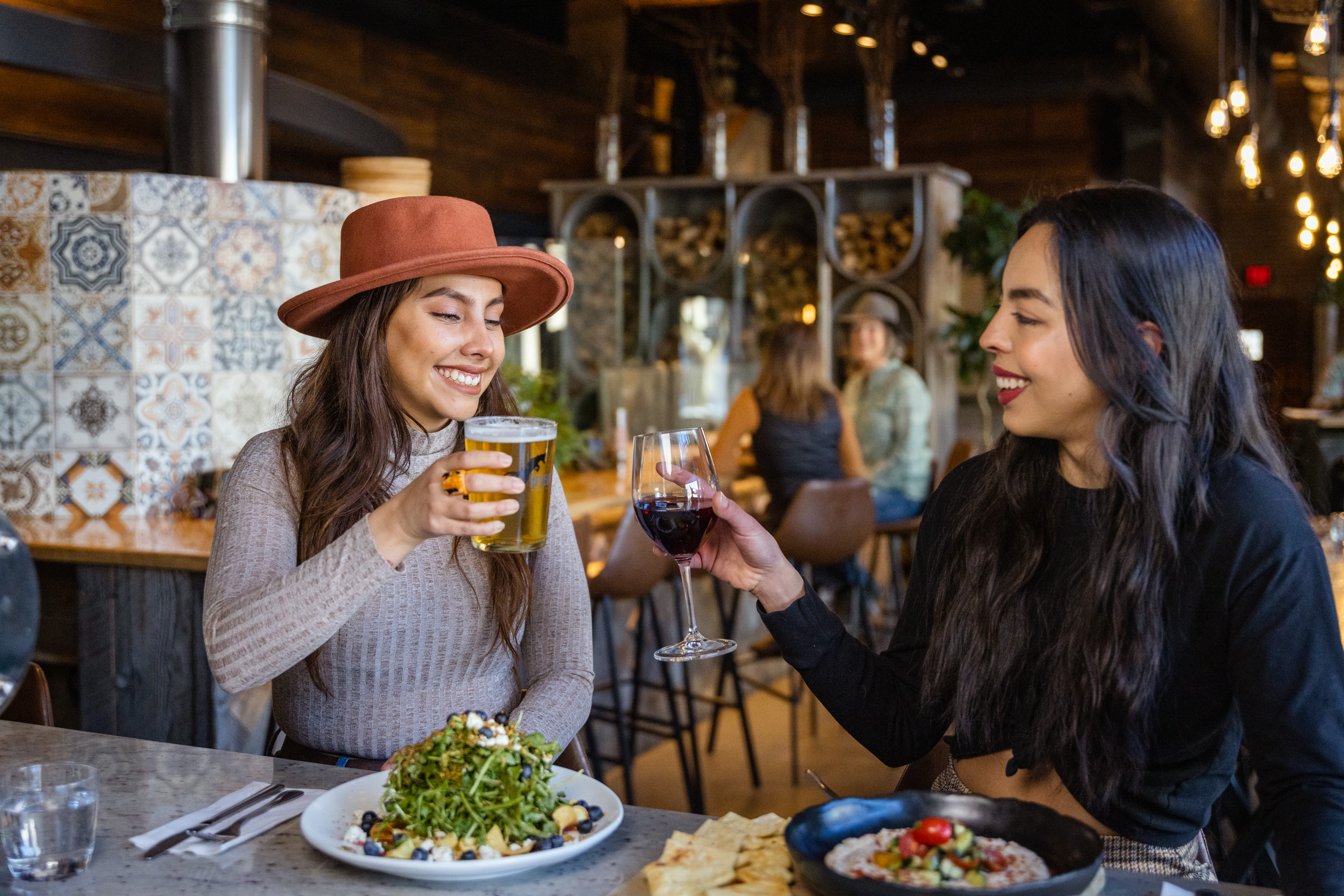 photo of 2 women toasting with drinks at a bar